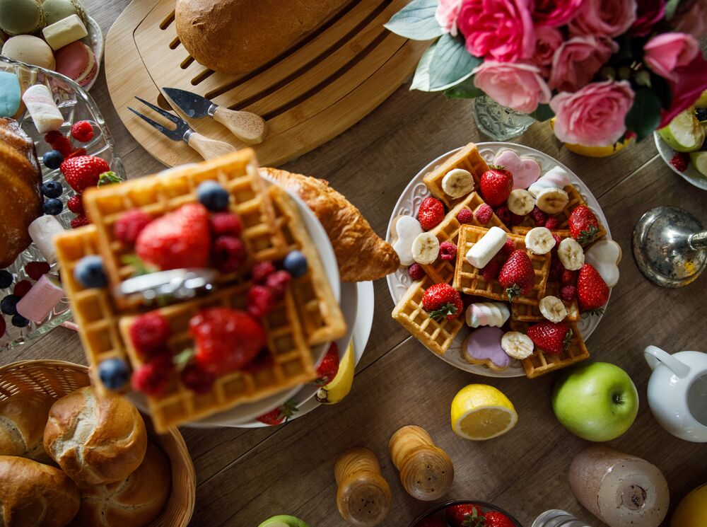 Brunch foods sit on a table including waffles, strawberries, apples, buns, and maple syrup at the Rimrock Resort in Banff National Park.